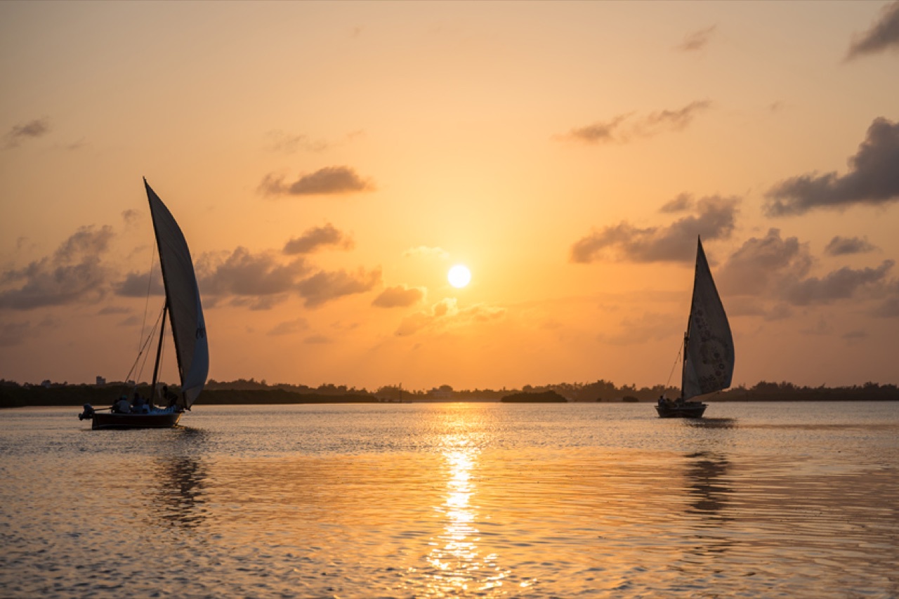 Two traditional dhows silhouetted against the Lamu sunset.
